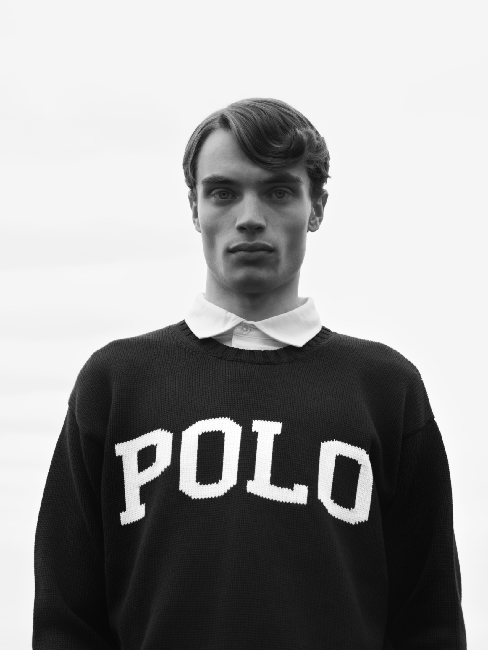 Black-and-white front-facing portrait of a model wearing a Polo sweater.