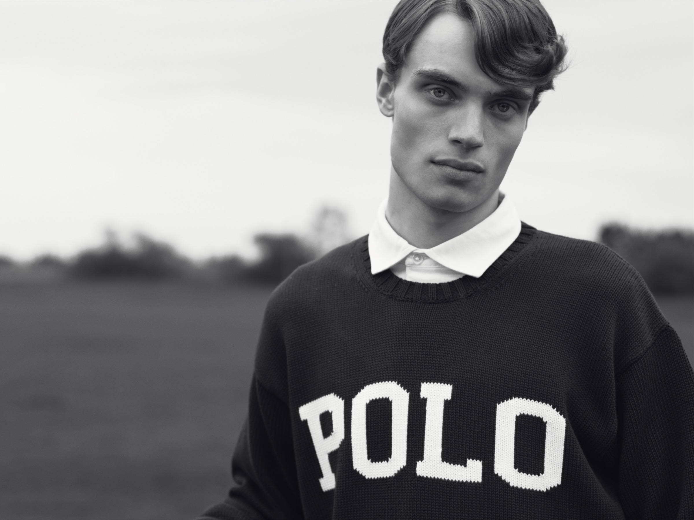 Black-and-white outdoor portrait of a model wearing a Polo sweater.