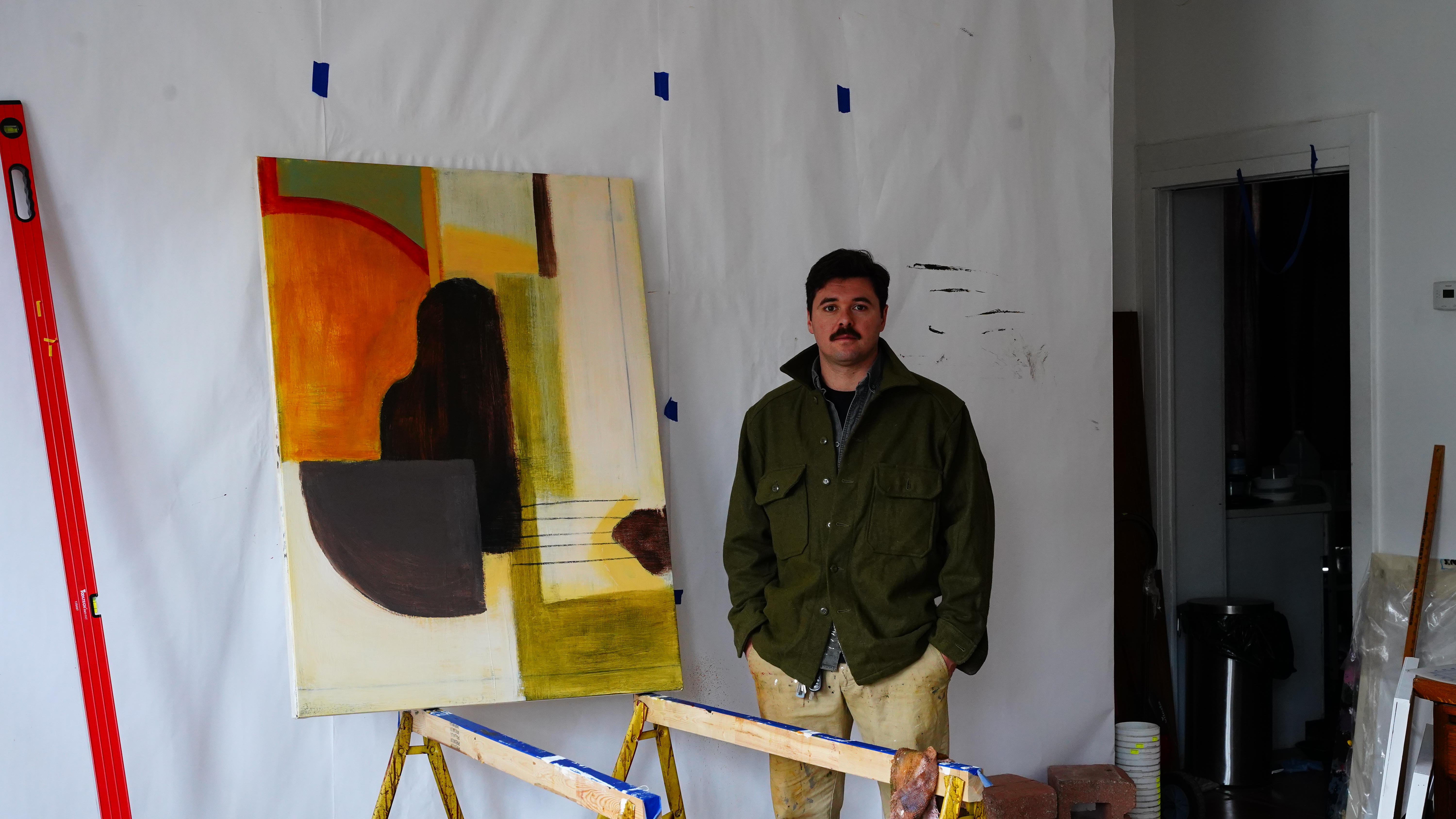 Studio portrait of Dante D'Ignazio standing beside a large painting.
