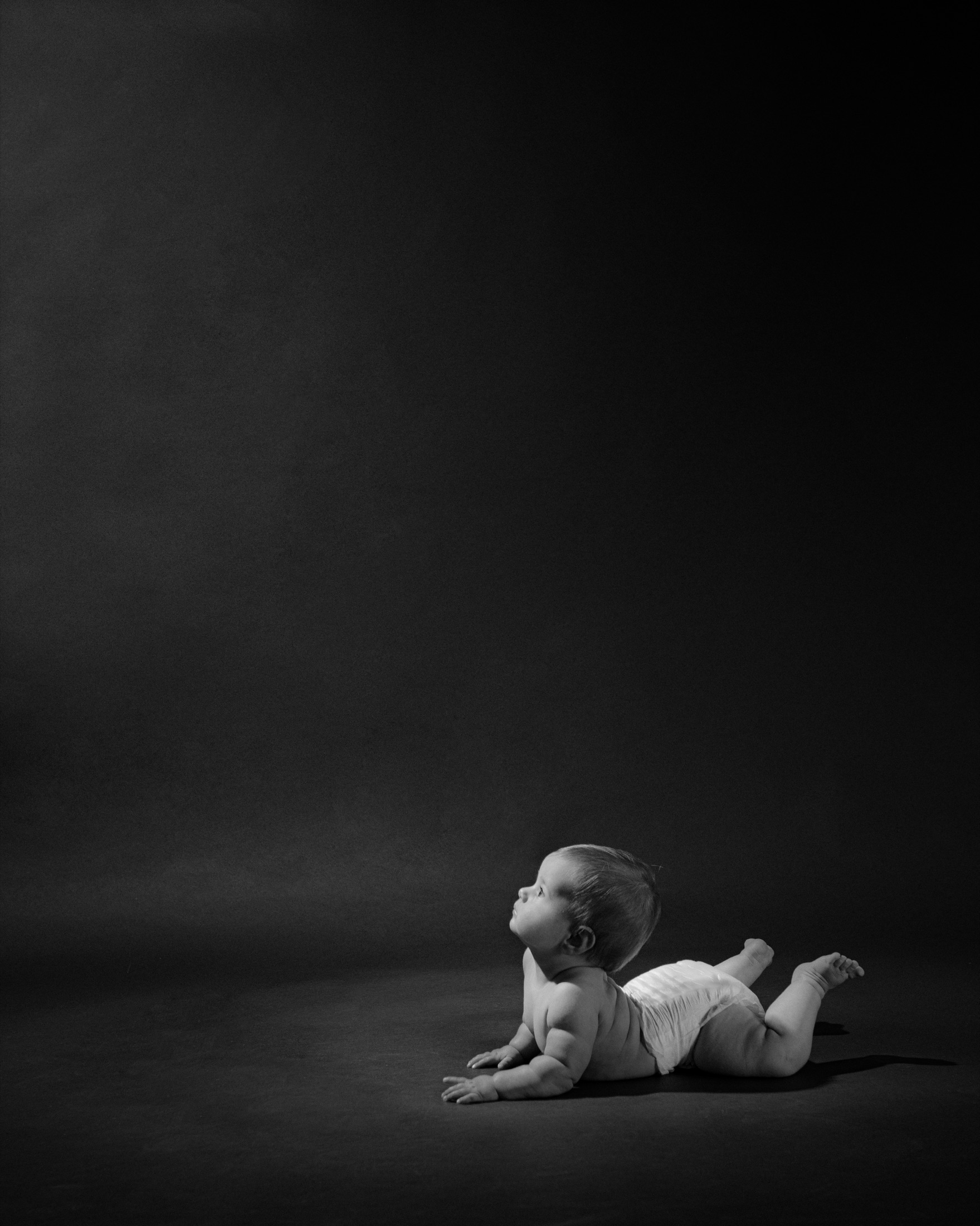 Black-and-white studio portrait of an infant looking upward.